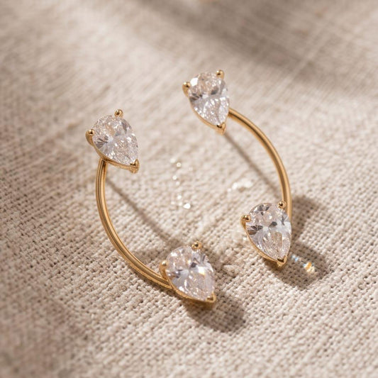 Pair of 18k gold-plated stainless steel Sasha ear jacket earrings featuring pear-shaped clear stones.